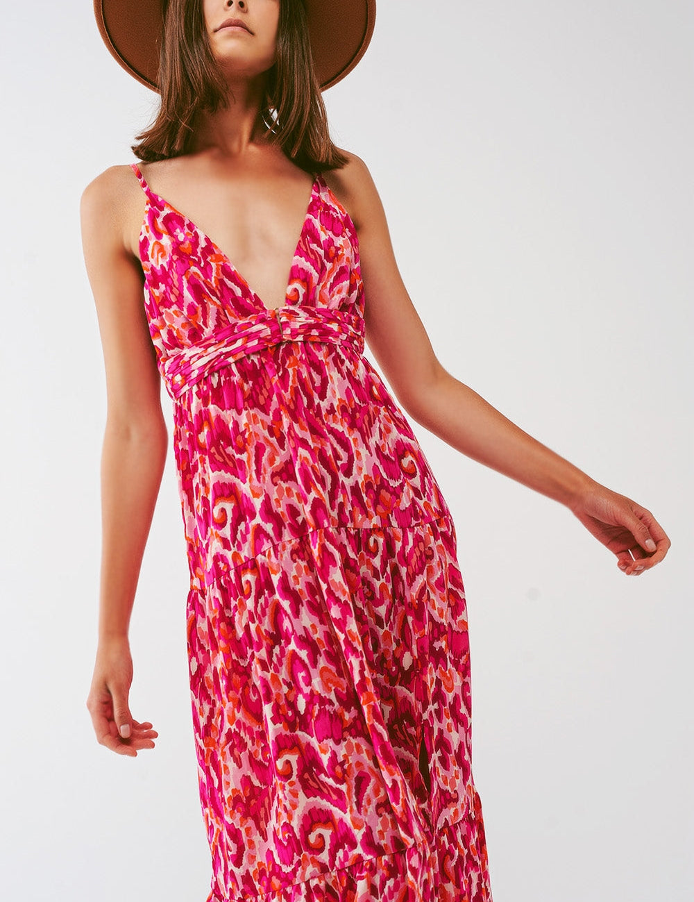 Woman wearing Floralia Pink Maxi Dress with floral pattern and V-neckline; showcasing romantic, flowing summer fashion with a hat.