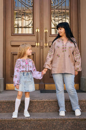 Mother and daughter in embroidered vyshyvanka blouses, standing on steps.
