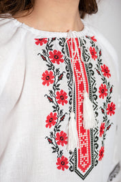 Close-up of girls' white vyshyvanka blouse with red and black floral embroidery, crafted in linen and cotton for traditional Ukrainian style.