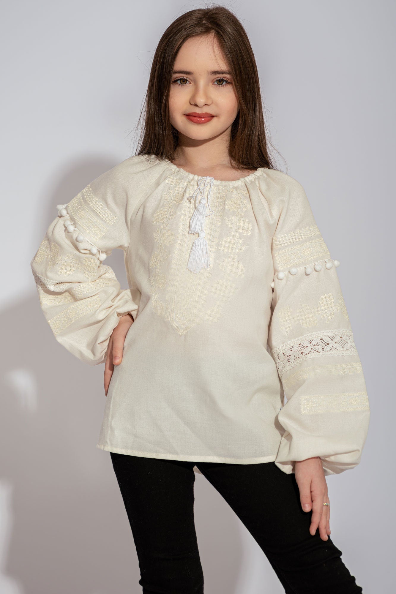 Girl wearing an embroidered white Ukrainian vyshyvanka blouse with floral patterns and lace accents.