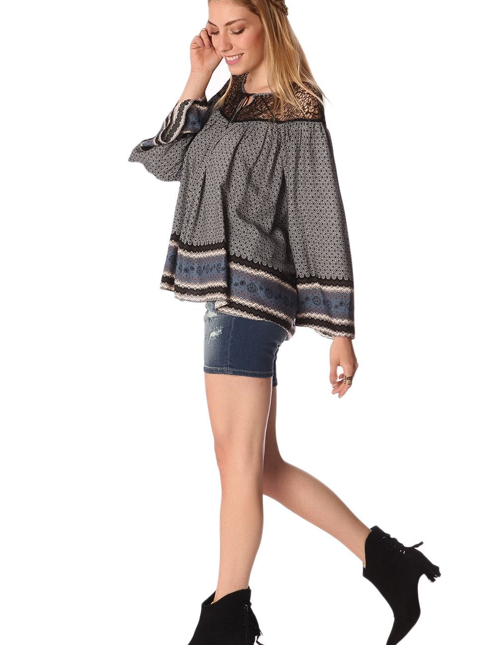 Woman wearing Elvarae Paisley Cage Blouse, showcasing gray paisley print, open neckline, and relaxed fit with denim shorts and black boots.