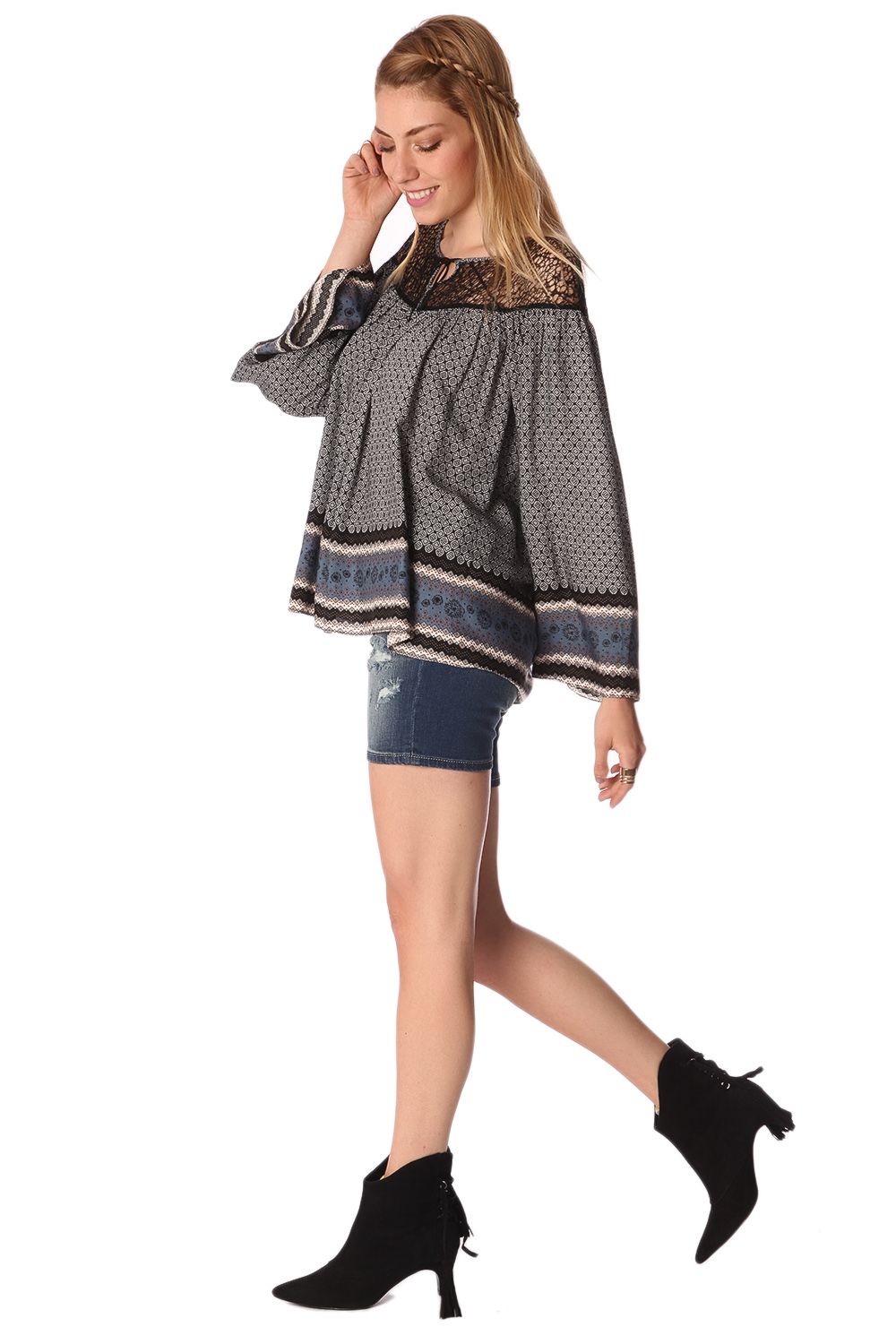 Woman wearing Elvarae Paisley Cage Blouse, showcasing gray paisley print, open neckline, and relaxed fit with denim shorts and black boots.