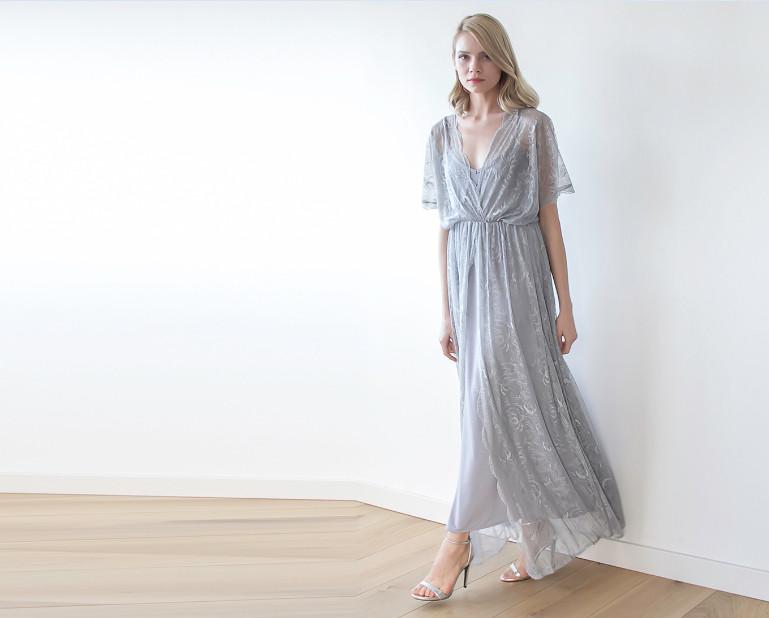 Woman wearing Velantra Sheer Lace Maxi Gown with floral lace, batwing sleeves, and high slit, showcasing elegant and romantic style.