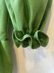Close-up of green embroidered sleeve detail on Ukrainian Vyshyvanka dress, showcasing traditional cross-stitch patterns.