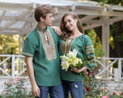 Couple wearing green Ukrainian Vyshyvanka blouses with traditional embroidery, standing in a garden, woman holding flowers.