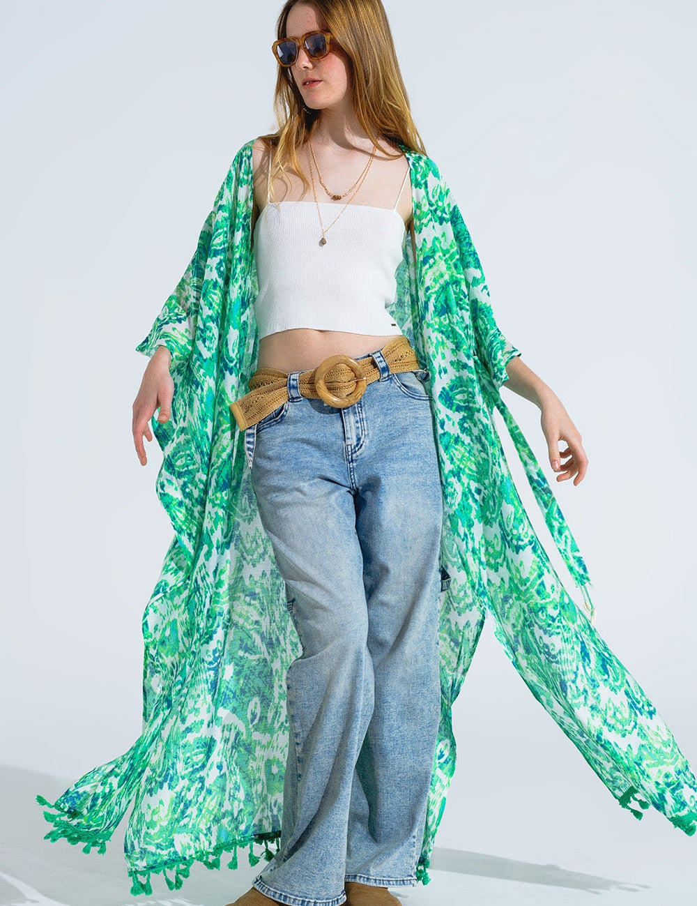 Woman wearing Arvella Green Boho Kimono with floral print and fringe trim, paired with a white top and jeans.