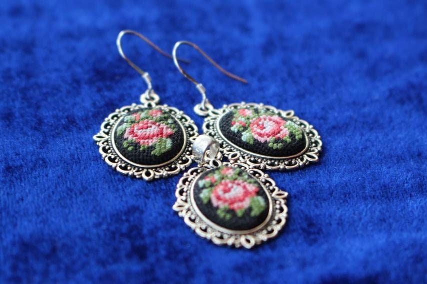 Hand-embroidered jewelry set with floral bouquet pendant and earrings on blue background, Petit Point silk design.