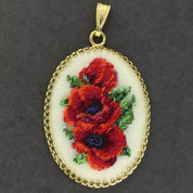 Hand-embroidered floral pendant necklace with Petit Point silk embroidery on gold frame, showcasing intricate red and green design.