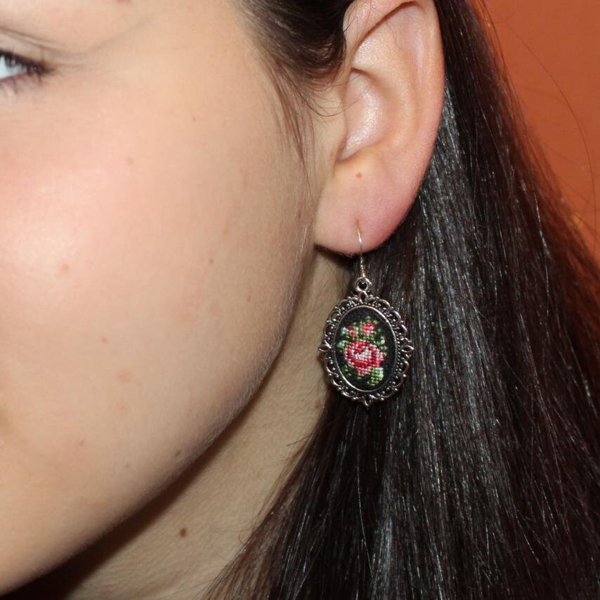 Woman wearing hand-embroidered petit point silk earring with floral bouquet design.