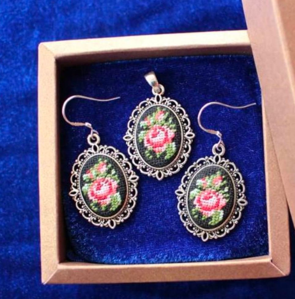 Hand-embroidered jewelry set with floral bouquet, featuring Petit Point silk pendant and earrings on a blue background.