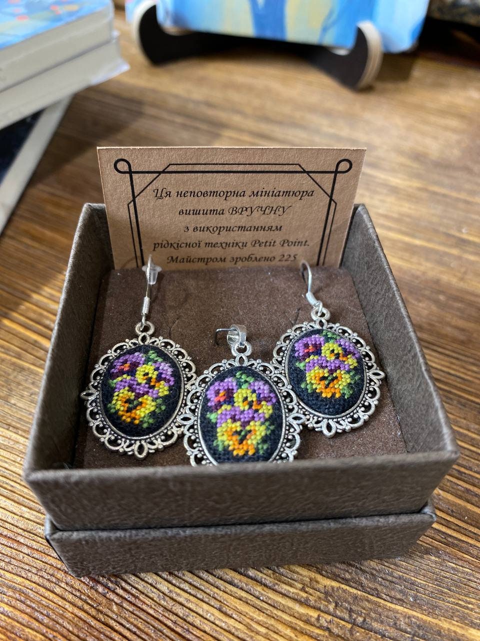 Hand-embroidered jewelry set with floral design, featuring Petit Point pendant and earrings in gift box on wooden table.