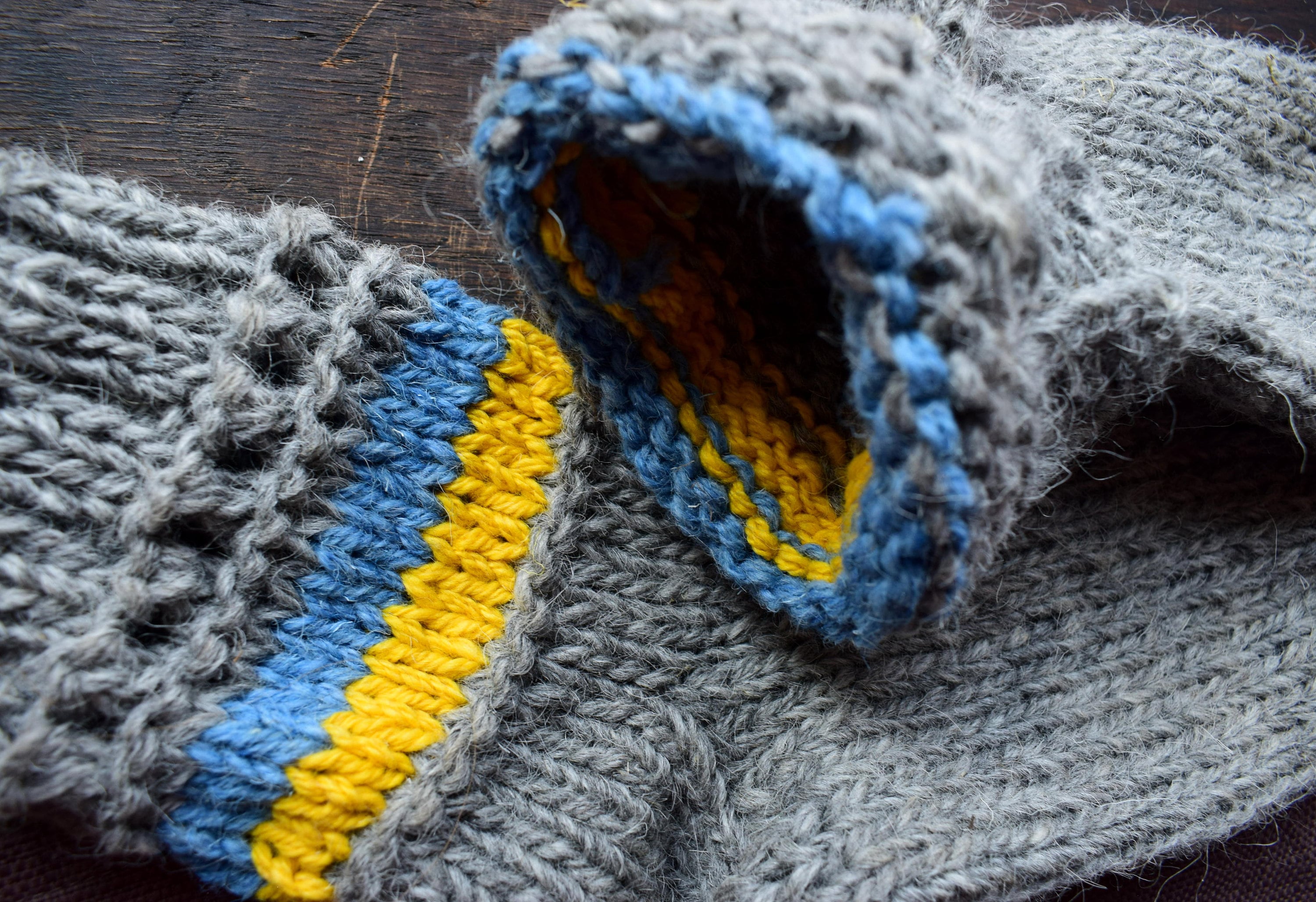 Hand-knitted grey woolen socks with Ukrainian flag colors, featuring blue and yellow accents, made from 100% natural wool.