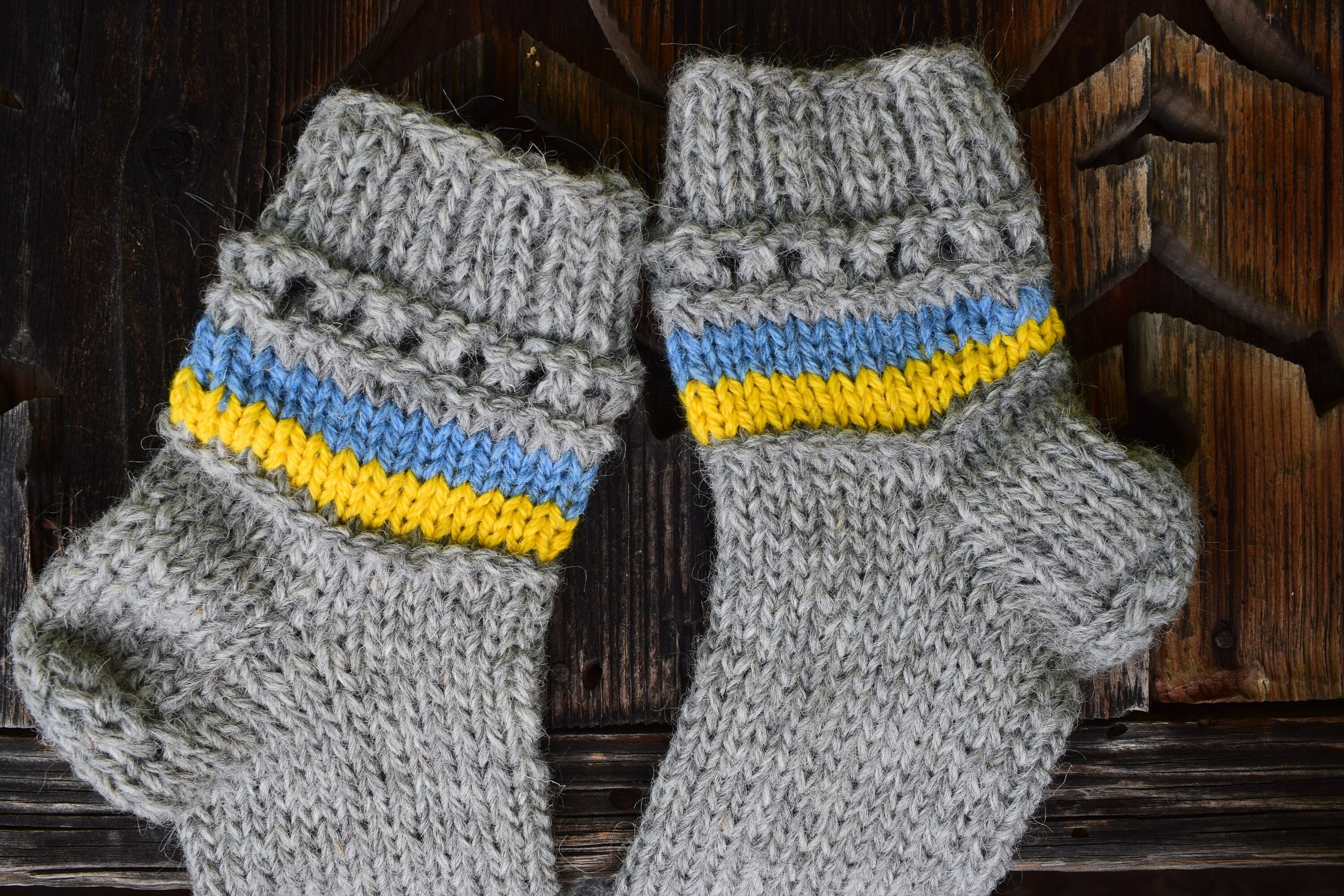 Hand-knitted grey woolen socks with Ukrainian flag colors, blue and yellow accents, made from 100% natural wool.