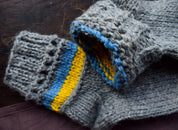 Hand-knitted grey woolen socks with Ukrainian flag colors, featuring blue and yellow accents, 100% natural wool, cozy winter wear.
