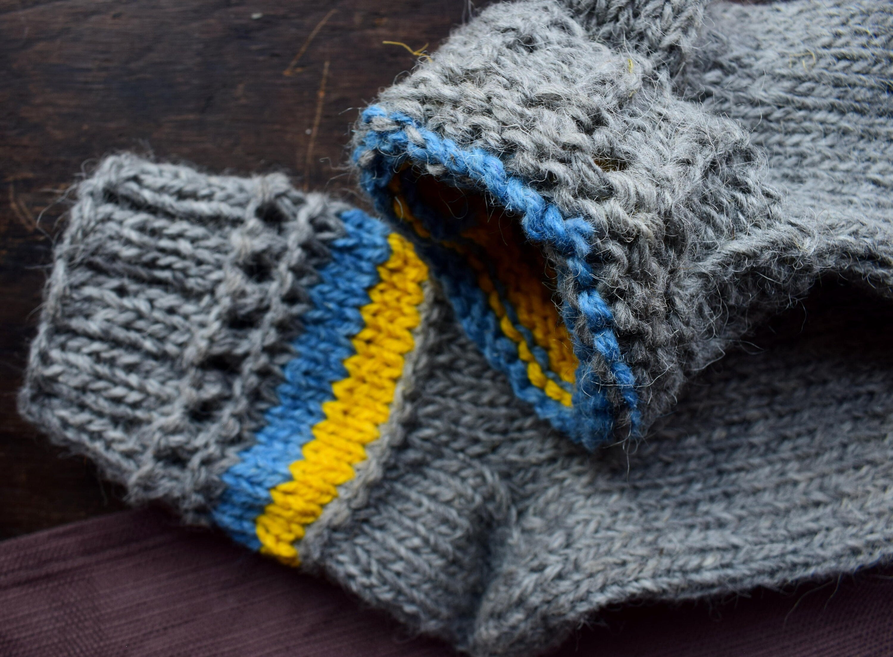 Hand-knitted grey woolen socks with Ukrainian flag colors, featuring blue and yellow accents, 100% natural wool, cozy winter wear.