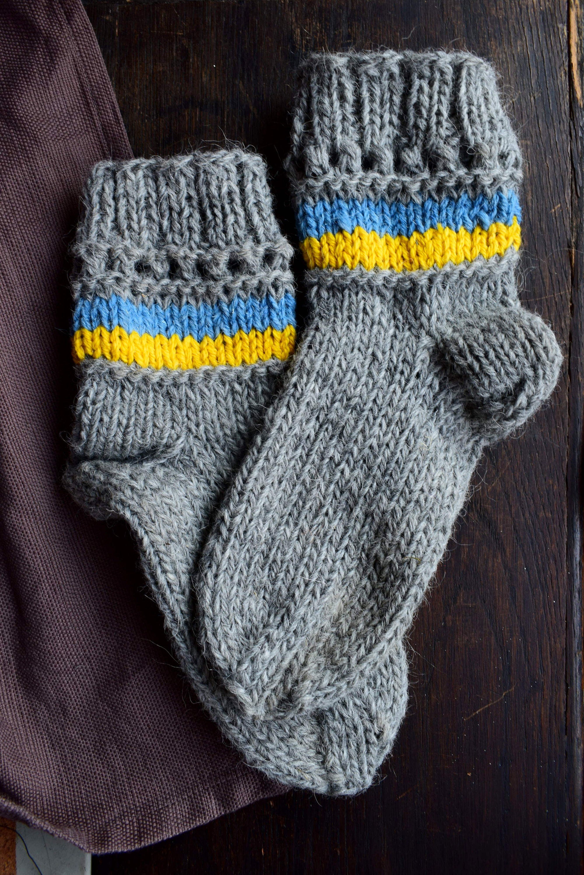 Hand-knitted grey woolen socks with Ukrainian flag colors, blue and yellow accents, made from 100% natural wool for warmth and comfort.