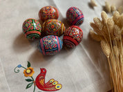 Set of 6 hand-painted Easter wooden eggs featuring traditional Ukrainian pysanky art with intricate folk designs on a tablecloth.