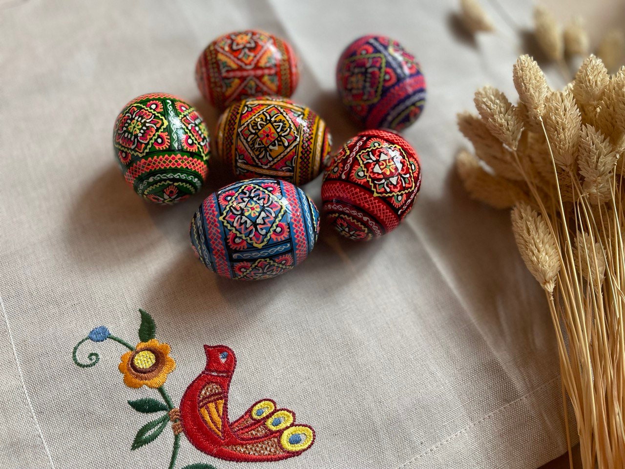 Set of 6 hand-painted Easter wooden eggs featuring traditional Ukrainian pysanky art with intricate folk designs on a tablecloth.