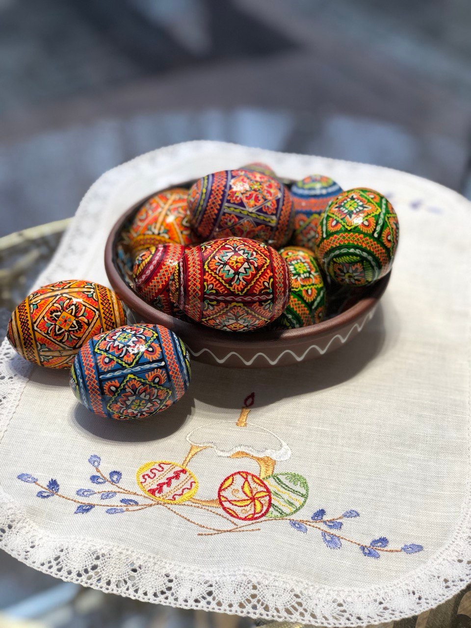 Set of hand-painted Ukrainian Easter wooden eggs with traditional pysanky designs in a bowl on an embroidered tablecloth