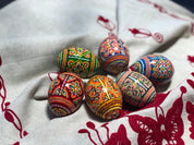 Set of 6 hand-painted Ukrainian pysanky Easter eggs with intricate folk designs on linen fabric.