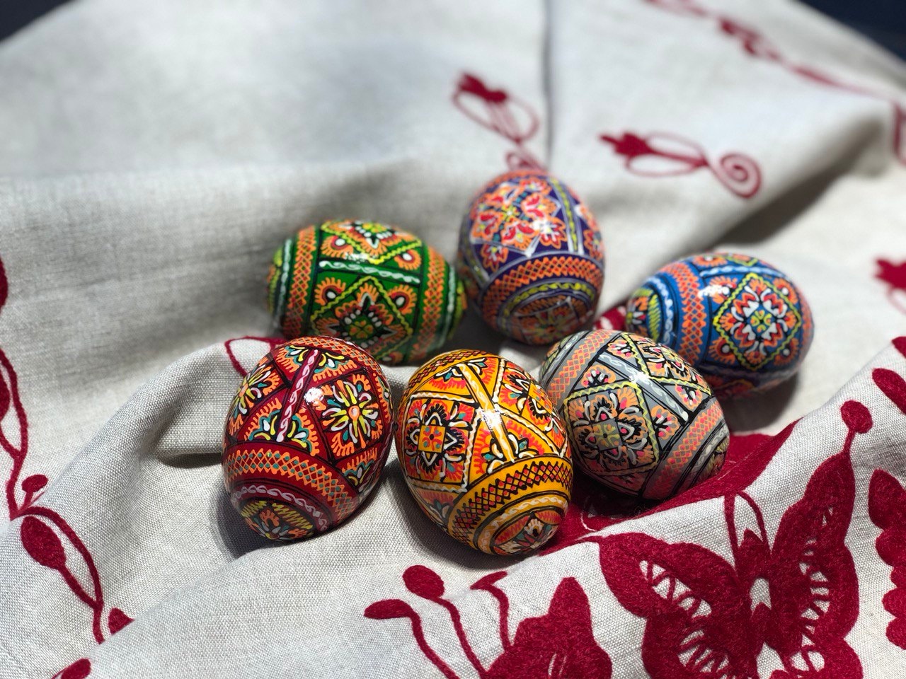 Set of 6 hand-painted Ukrainian pysanky Easter eggs with intricate folk designs on linen fabric.