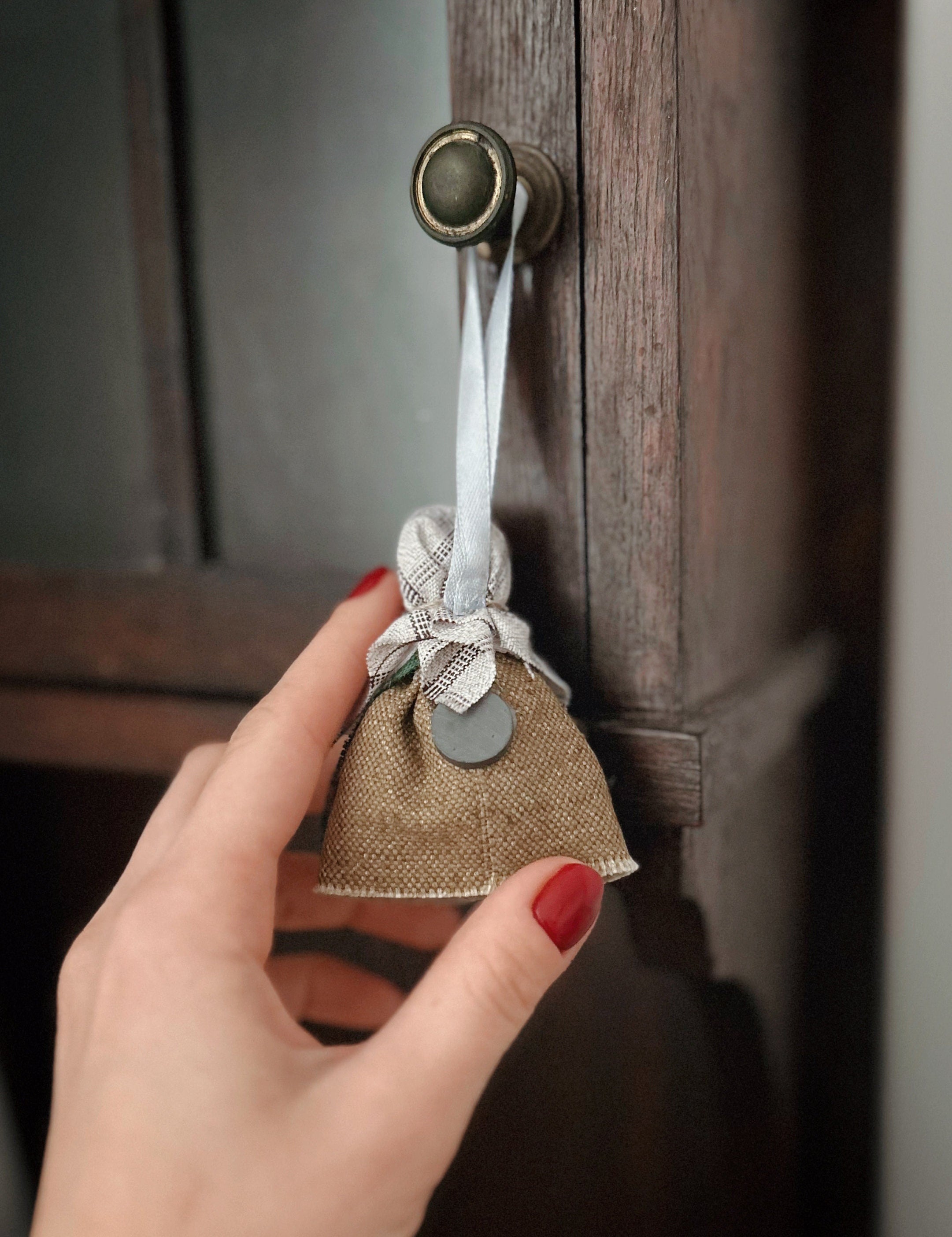 Handmade Ukrainian doll charm on cabinet knob, showcasing Motanka craft as a unique home decor piece with a symbolic horseshoe.