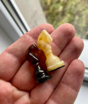 Handcrafted Baltic amber chess knights in hand, showcasing exquisite natural craftsmanship for collectors and chess enthusiasts.