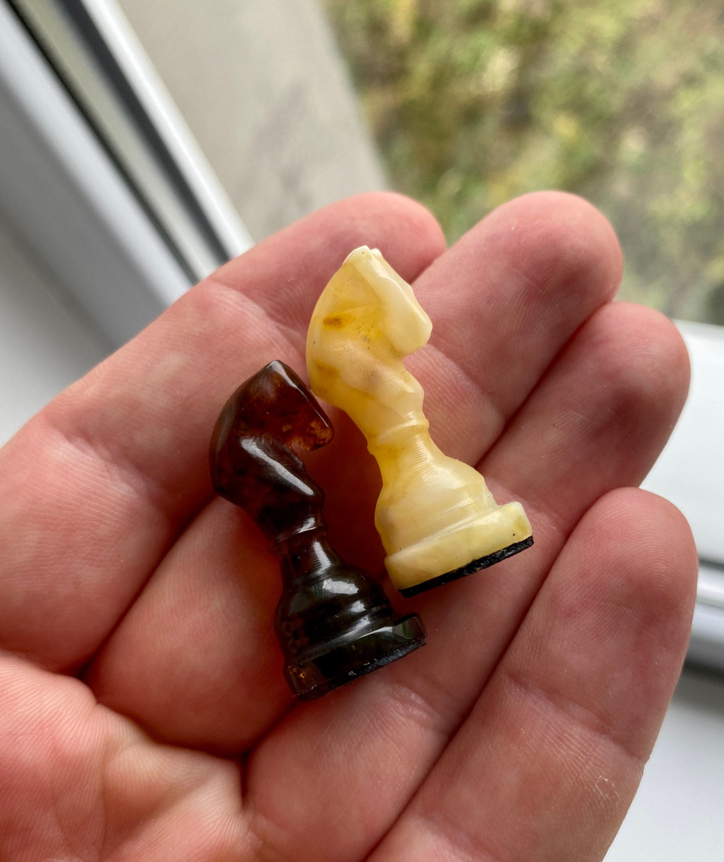 Handcrafted Baltic amber chess knights in hand, showcasing exquisite natural craftsmanship for collectors and chess enthusiasts.
