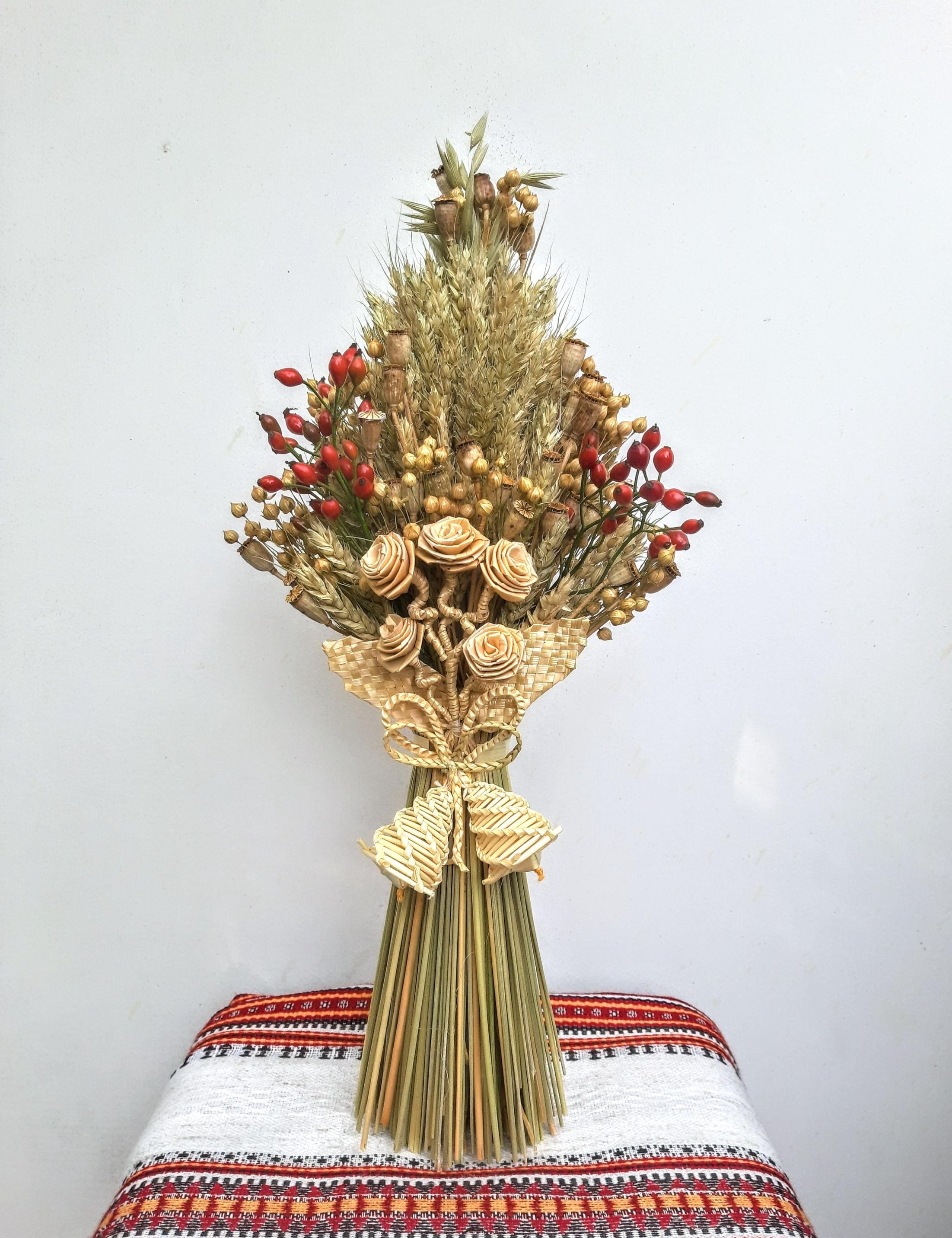 Handcrafted Ukrainian Didukh with wheat and dried flowers on traditional cloth, symbolizing holiday peace and prosperity.