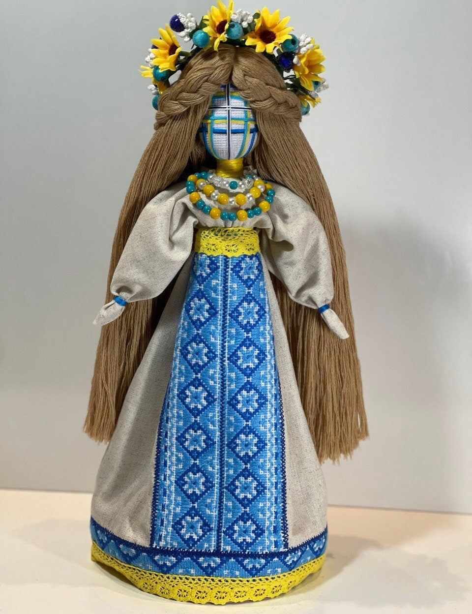 Handcrafted Ukrainian Motanka Doll with Embroidered Dress and Floral Crown on Wooden Stand