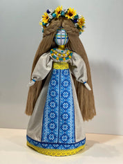 Handcrafted Ukrainian Motanka doll with blue embroidery, adorned with sunflower crown, symbolizing Ukrainian heritage and prosperity.