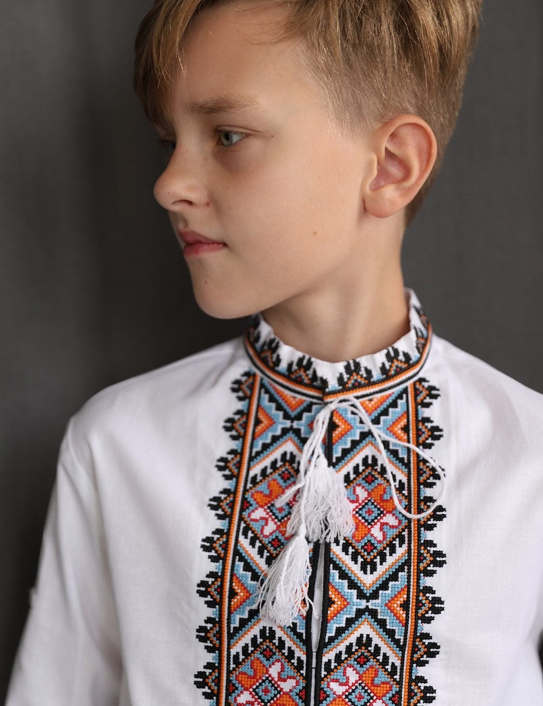 Boy wearing handmade Ukrainian Vyshyvanka, a white cotton shirt with traditional embroidered cross-stitch design.