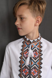 Boy wearing handmade Ukrainian Vyshyvanka, a white cotton shirt with traditional embroidered cross-stitch design.