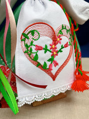 Handmade Motanka doll detail with heart embroidery, showcasing colorful ribbons and intricate lace, symbolizing Ukrainian folk art.