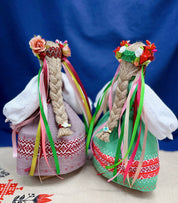 Handmade Motanka dolls in traditional Ukrainian attire, featuring colorful ribbons and floral crowns against a blue background.