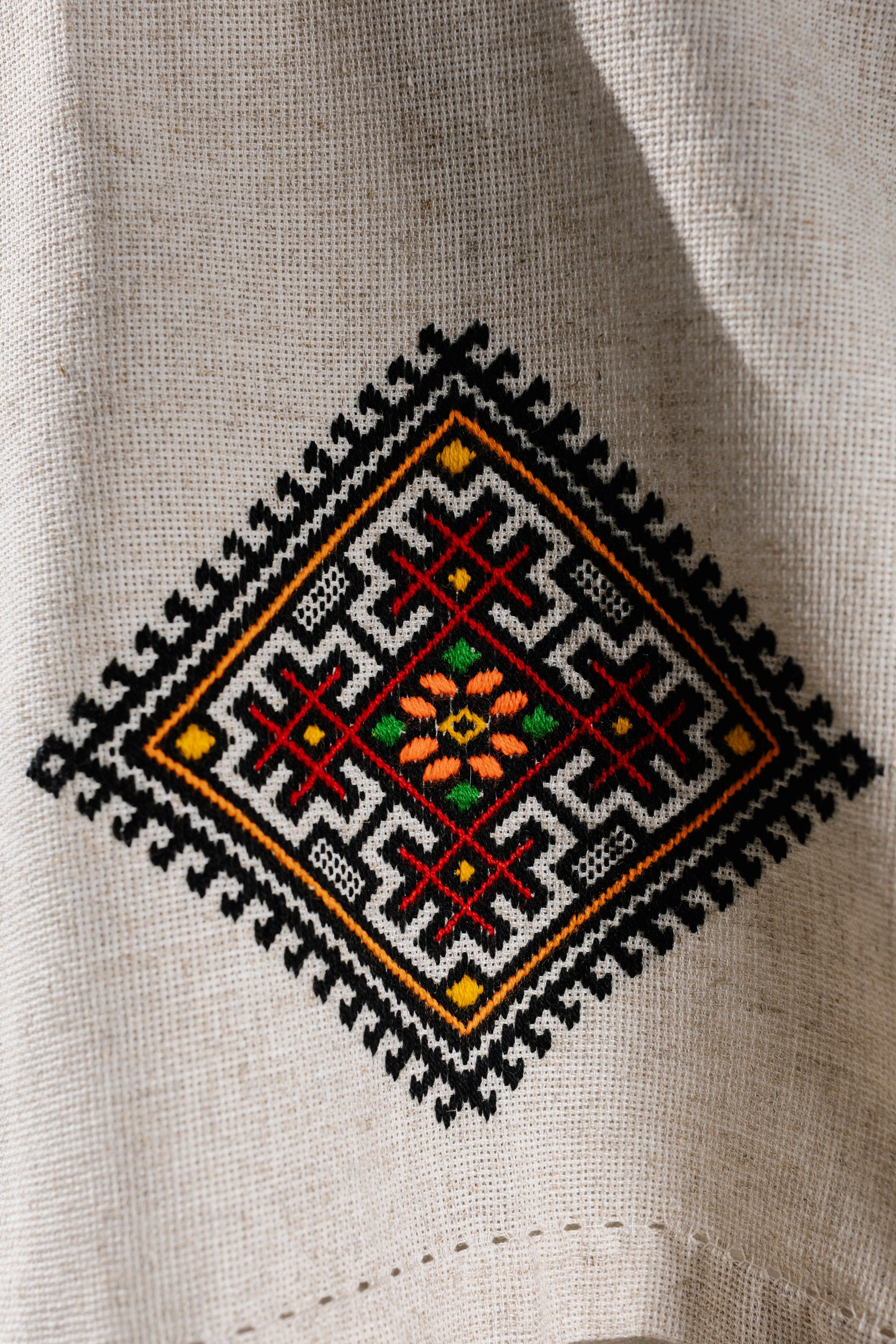 Close-up of Ukrainian embroidered tablecloth with traditional ethnic design in vibrant colors on linen fabric.