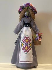 Handmade Ukrainian Motanka Bereginya doll with floral headpiece and embroidered dress on wooden stand, symbolizing protection and prosperity.