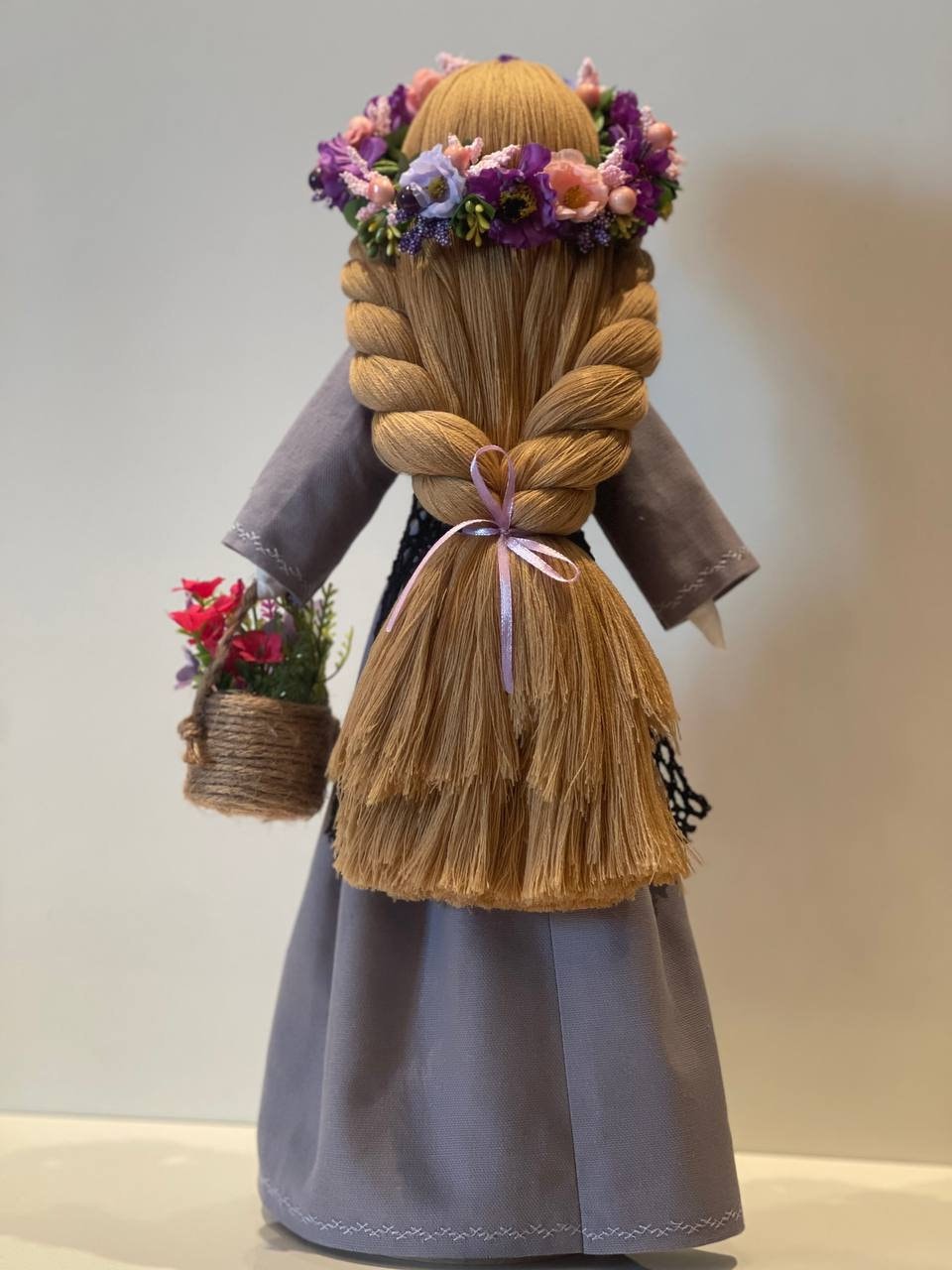 Handmade Ukrainian Bereginya Motanka doll with braided hair and flower crown, on wooden stand, for home protection and Easter gift.