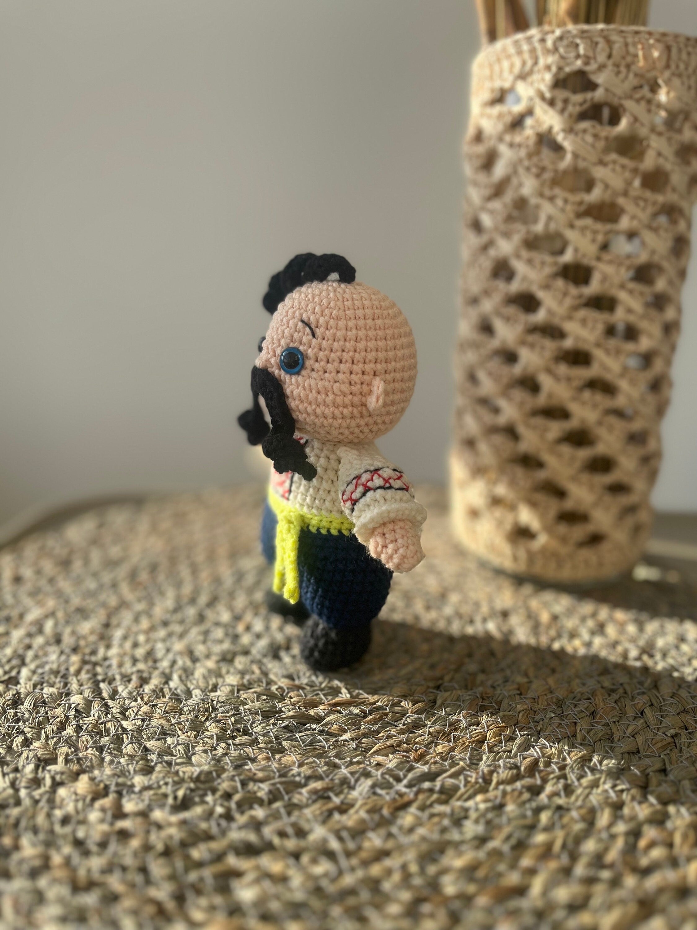 Handmade crochet Cossack doll, Ukrainian folk art, ethnic home decor on woven surface.