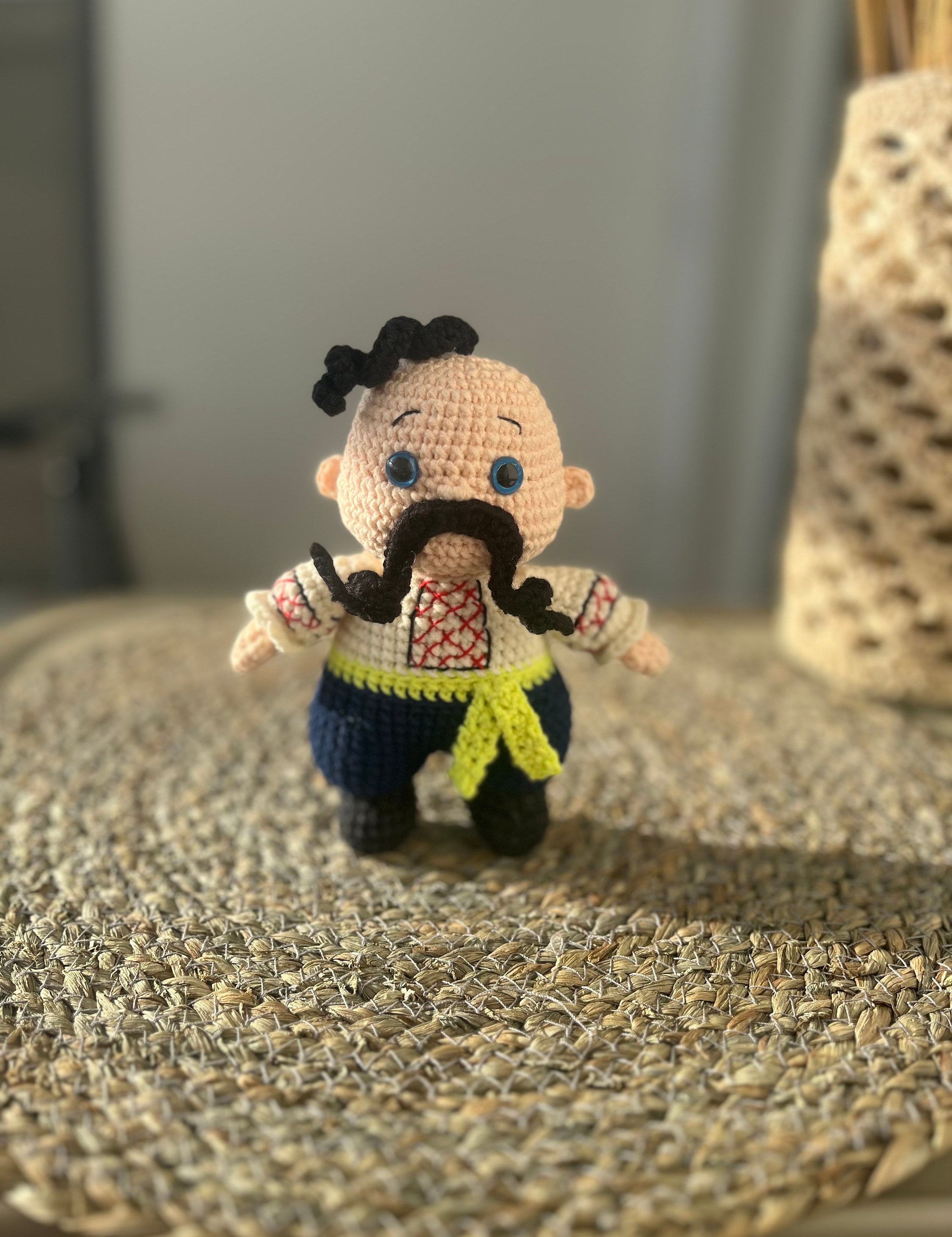 Handmade crochet Cossack doll, Ukrainian folk art, ethnic home decor, cultural gift on woven surface.