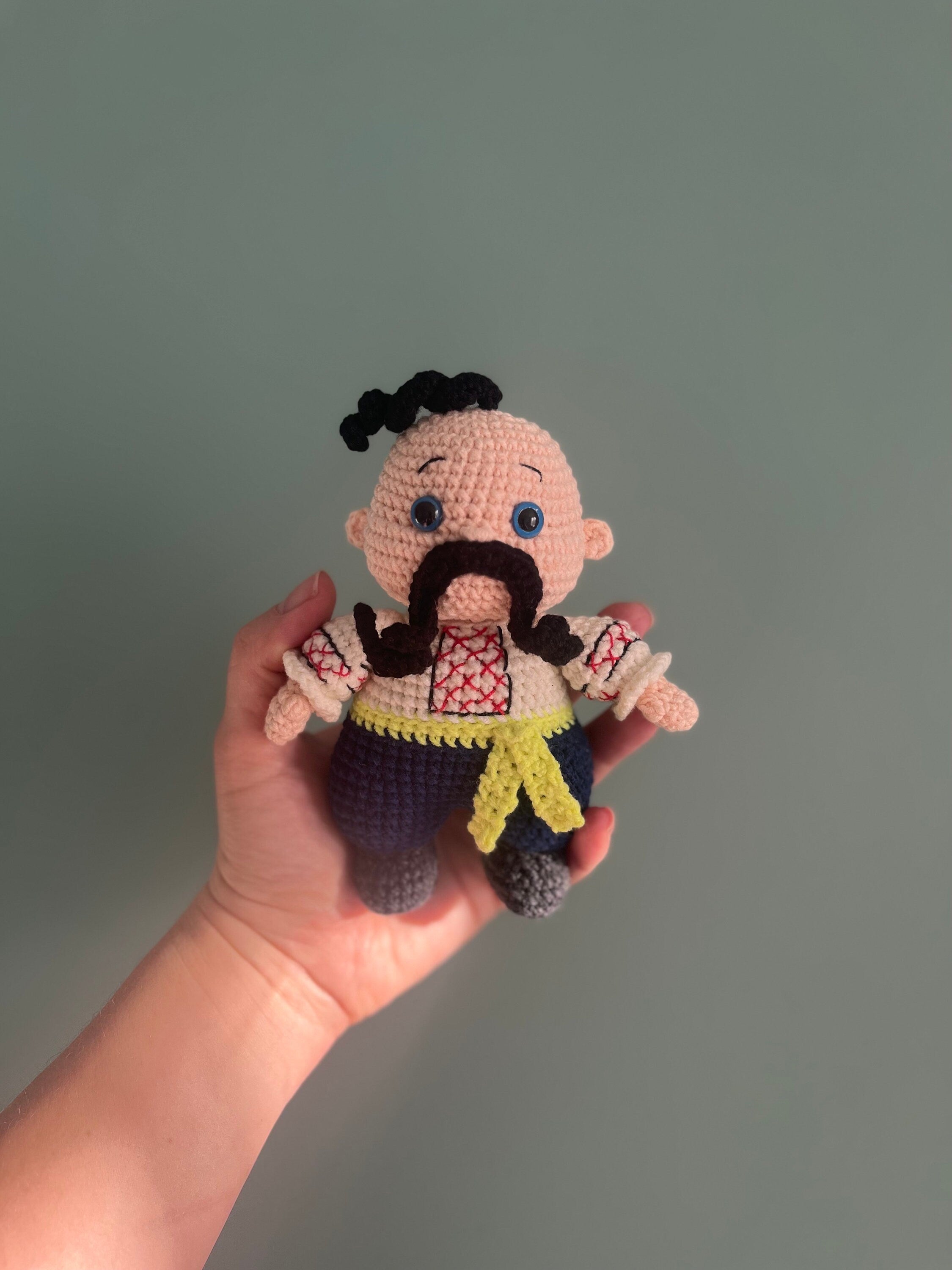 Handmade crochet Cossack doll, Ukrainian folk art souvenir held in hand for scale, ethnic home decor, unique cultural gift.