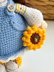 Handmade knitted doll holding a yellow flower, detailed Ukrainian themed toy in blue dress, perfect unique cultural keepsake.