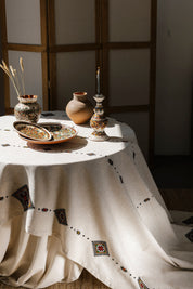 Handmade Ukrainian embroidered tablecloth with traditional ethnic designs, set on a dining table with decorative pottery.