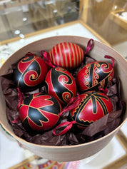 Set of 6 hand-painted Ukrainian Pysanky eggs in a box, featuring traditional red and black folk art designs with symbolic motifs.