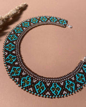 Handmade Ukrainian Sylyanka necklace with ceramic and turquoise beads on a brown background, featuring ethnic geometric patterns.