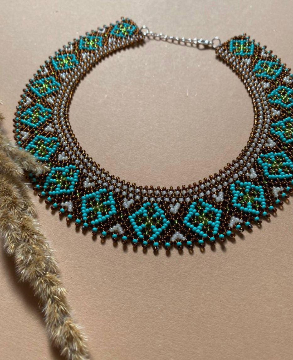 Handmade Ukrainian Sylyanka necklace with ceramic and turquoise beads, featuring ethnic geometric patterns on a beige background.