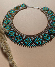 Handmade Ukrainian Sylyanka necklace with ceramic and turquoise beads, featuring ethnic geometric patterns on a beige background.