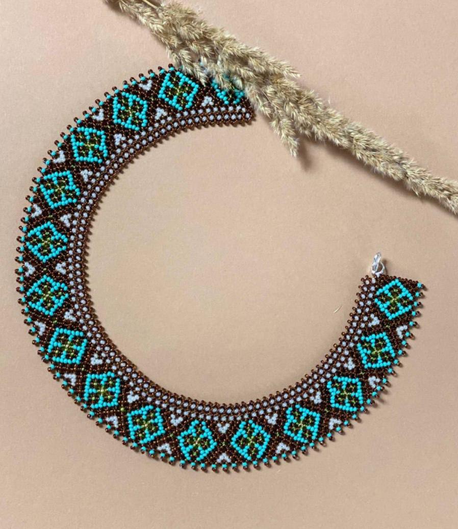Handmade Ukrainian sylyanka necklace with ceramic and turquoise beads, featuring ethnic geometric and floral patterns on beige background.