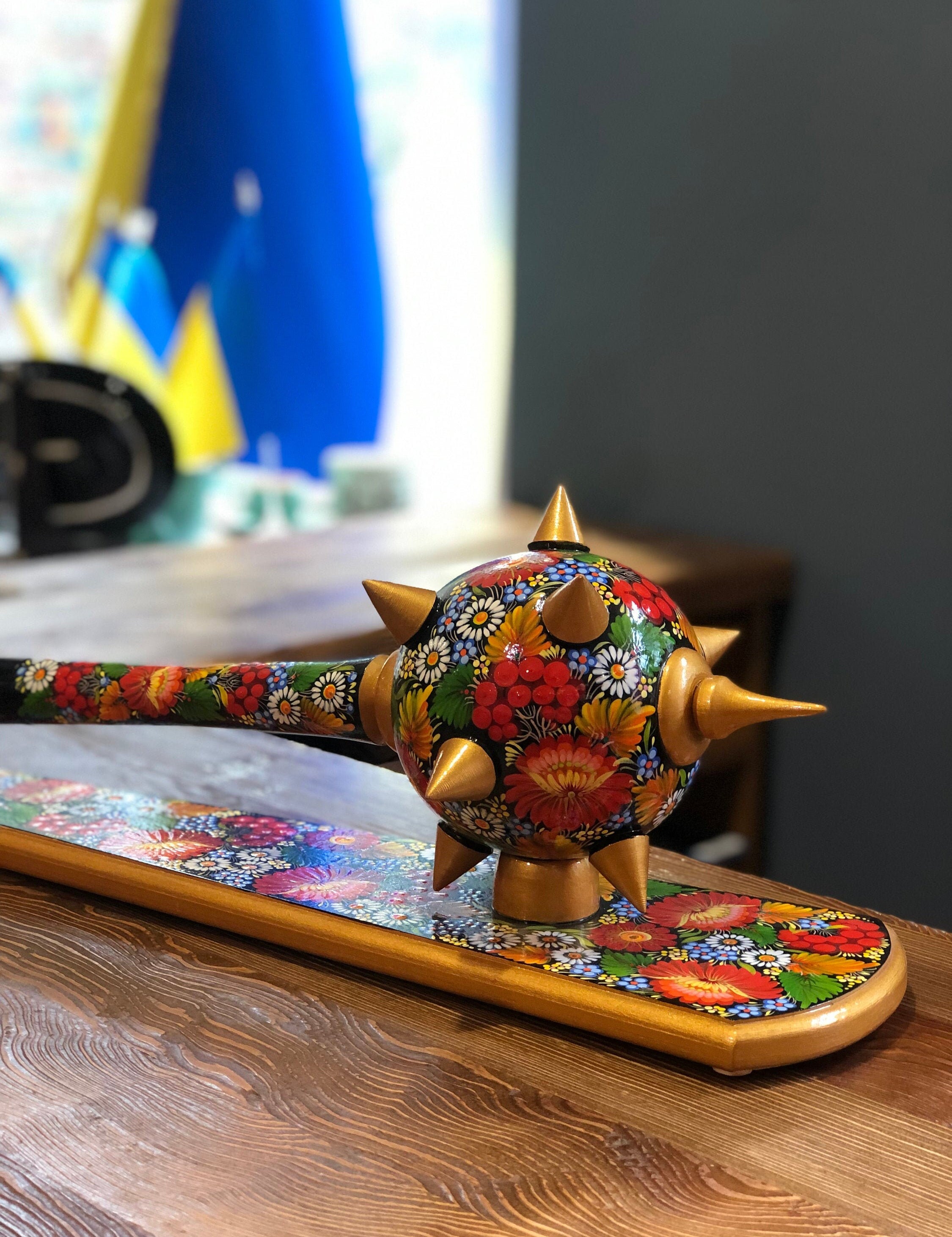 Handmade wooden Ukrainian Bulava with floral design, symbolizing leadership and cultural heritage, displayed on wooden surface.