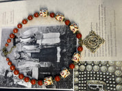Handmade Ukrainian necklace with white clay and jasper beads, featuring cast brass pendant on a vintage book background.